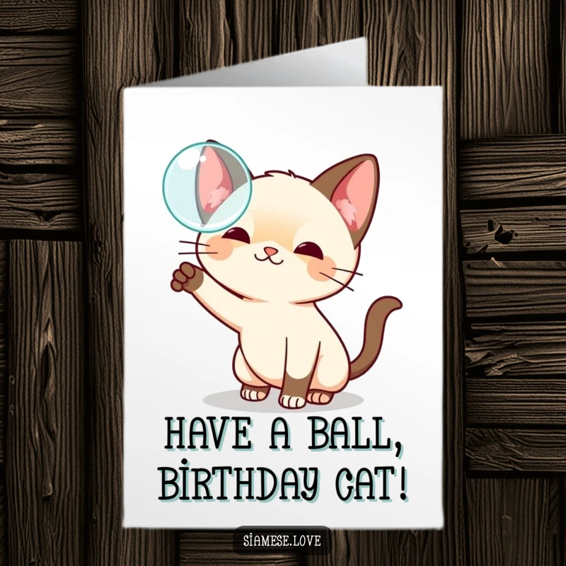 Funny Free Printable Birthday Card with a playful kawaii Siamese cat batting at a floating iridescent bubble with delight.