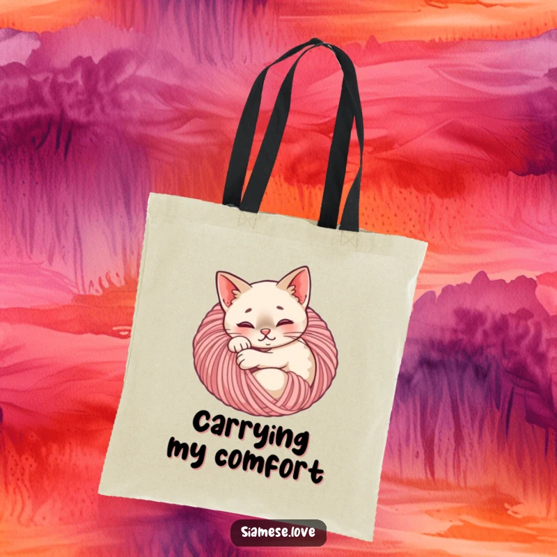 Funny Siamese cat tote bag depicting a content feline curled up inside a ball of yarn, a charming and practical accessory.