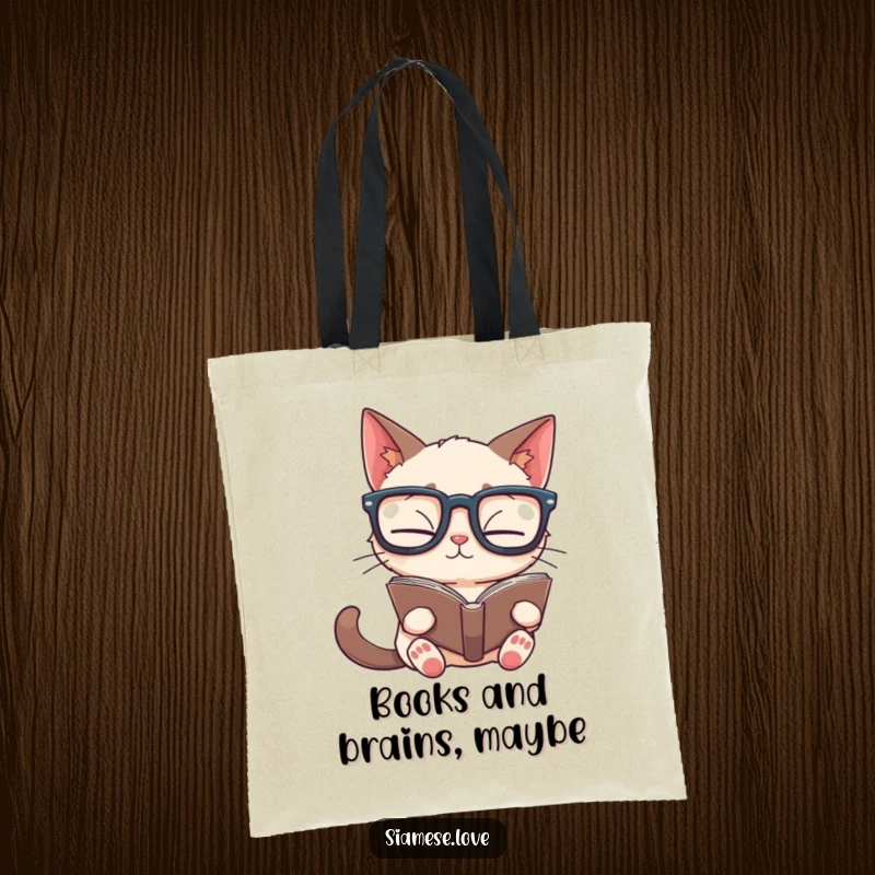 Funny Siamese cat tote bag showing a feline with big glasses reading a book upside down, a humorous accessory for bookworms.